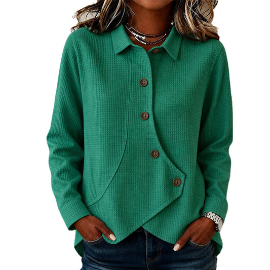 Model wearing the waffle-knit top in green, hands in jeans pockets, showing the collar, brown buttons and curved asymmetric hem. 2