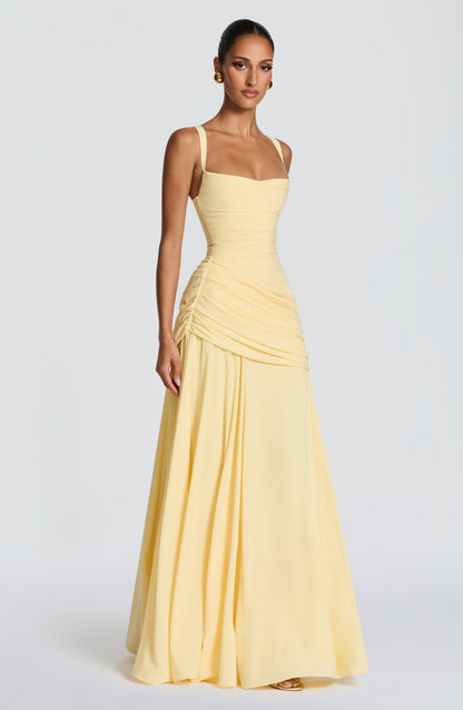 Three-quarter side view of the pale yellow dress, showing the ruched side seam, wide straps and full floor-length skirt. 3