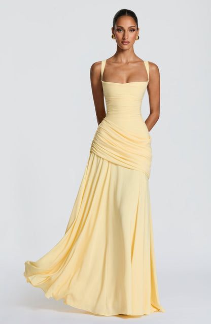 Front view of the pale yellow chiffon maxi dress on a model, showing the square neckline, draped hip detail and flowing skirt. 1