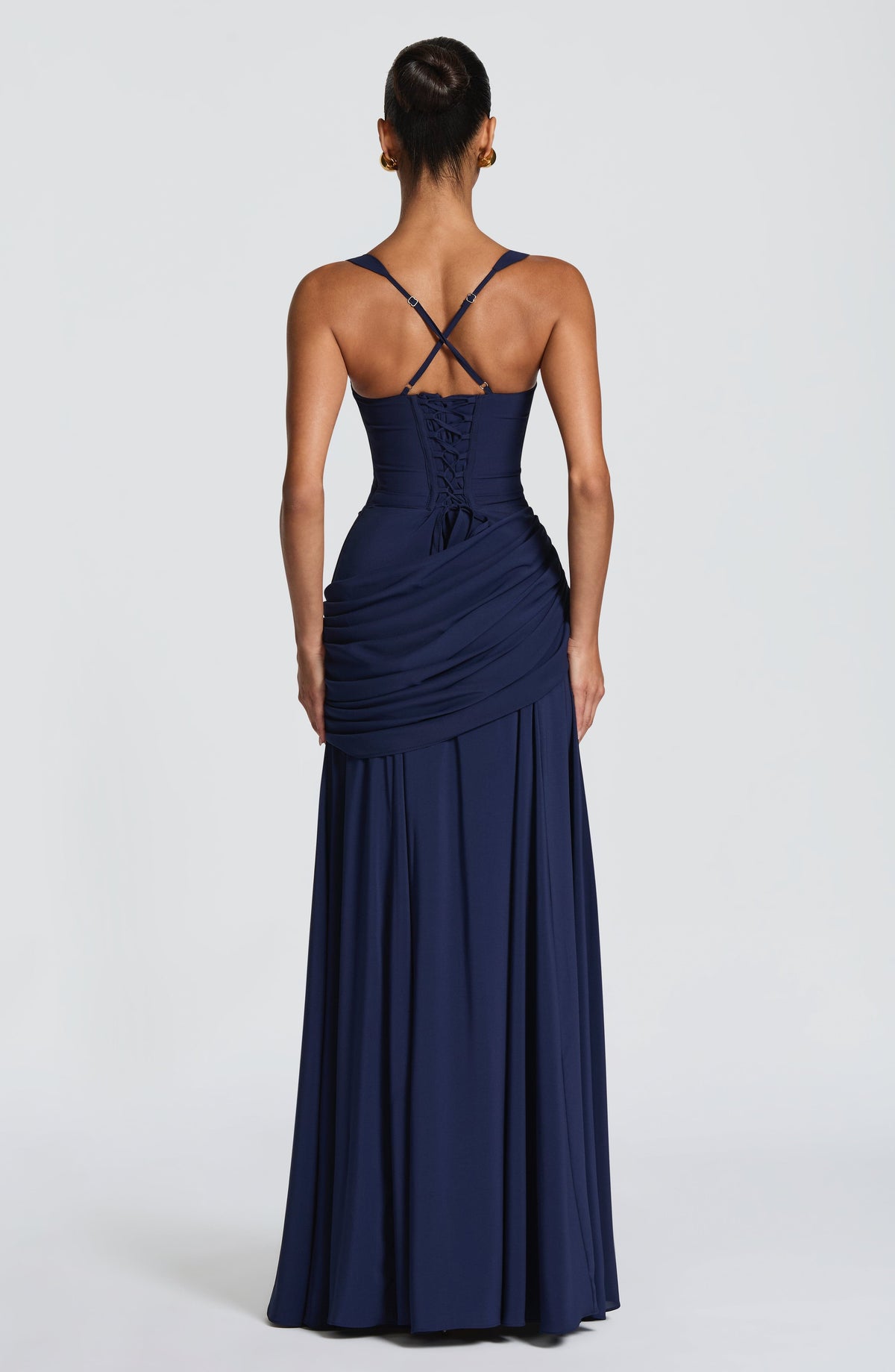 Back view of the navy dress showing the corset-style lace-up back, crossed adjustable straps and the draped panel at the hip. 11