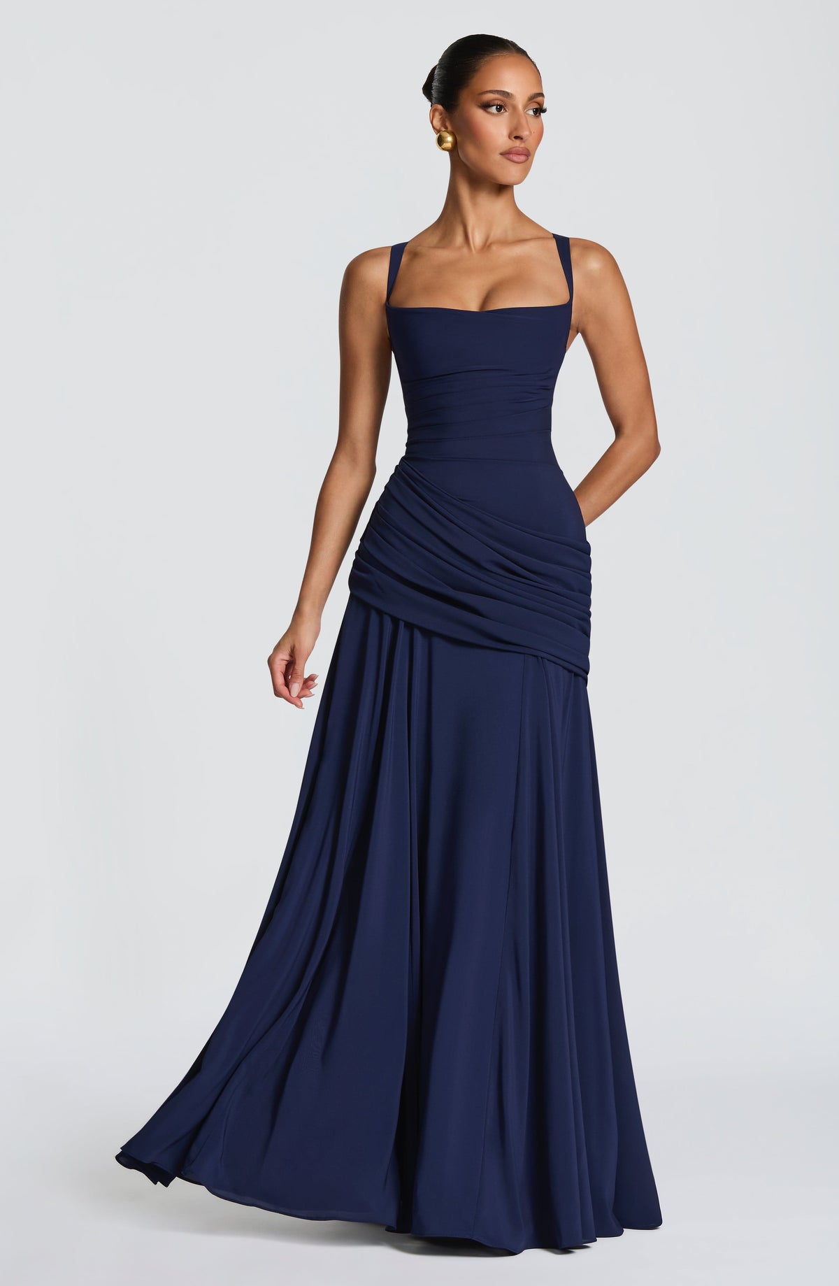 Navy dress in a three-quarter front view with the model stepping forward, showing the skirt flowing in movement. 8