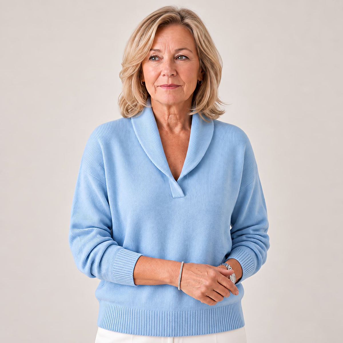 Woman gazing to the side in the jumper in pale blue, hands held together at the waist. 6
