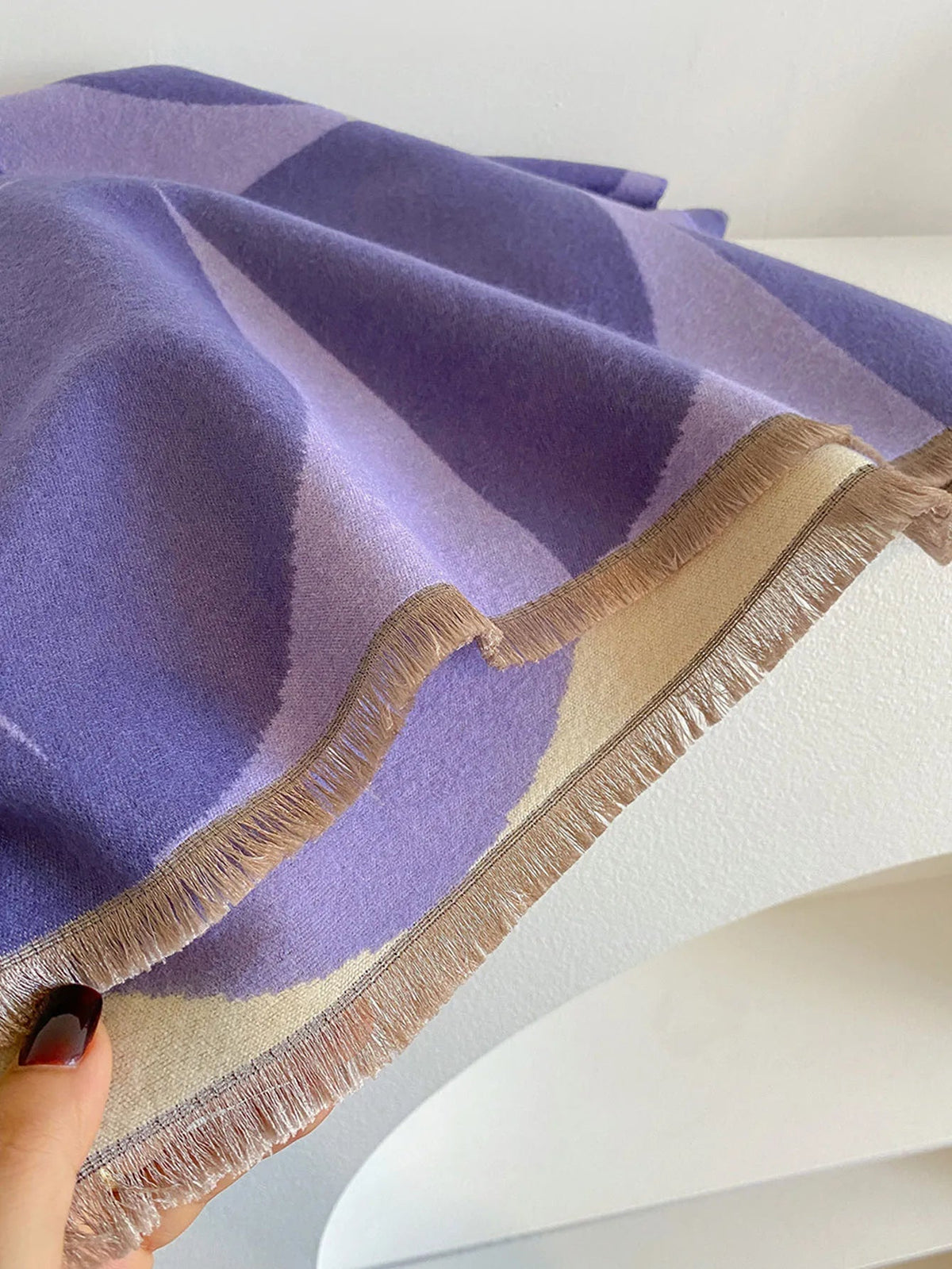 Close-up of the purple and cream scarf held by a hand, showing the neat fringe along its short end. 11