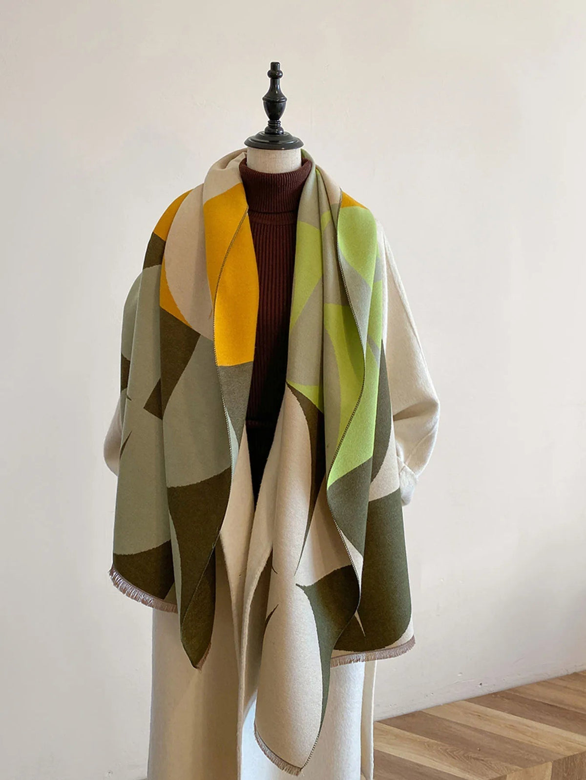 Scarf in yellow, lime green, olive and cream geometric blocks draped open over a mannequin with a burgundy polo neck. 4