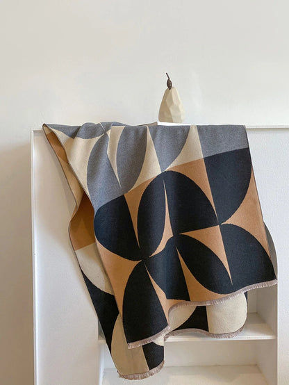 Black, camel, grey and cream geometric scarf hanging over a white shelf, with the large leaf-like shapes clearly visible. 8