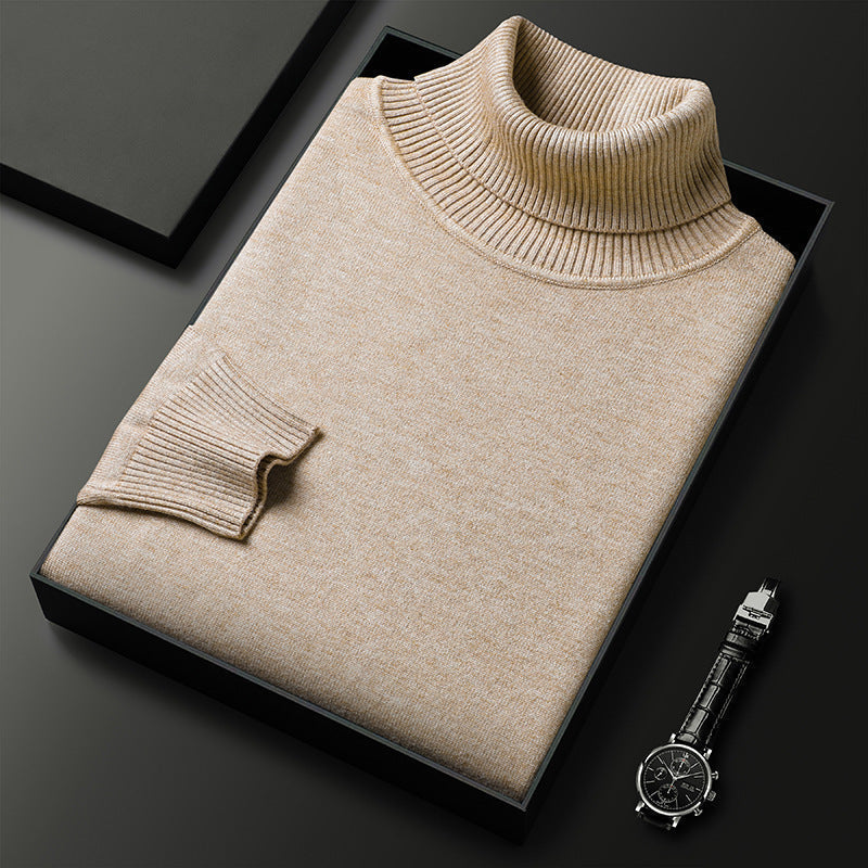 Folded beige roll-neck jumper with ribbed collar and cuff in a black box, beside a black-strapped wristwatch. 1