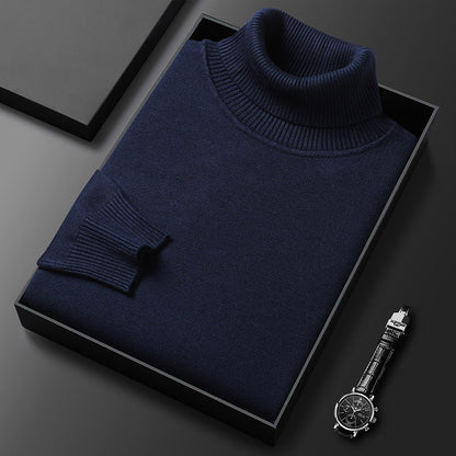 Folded navy roll-neck jumper with ribbed collar and cuff in a black gift box, a wristwatch at the corner. 4